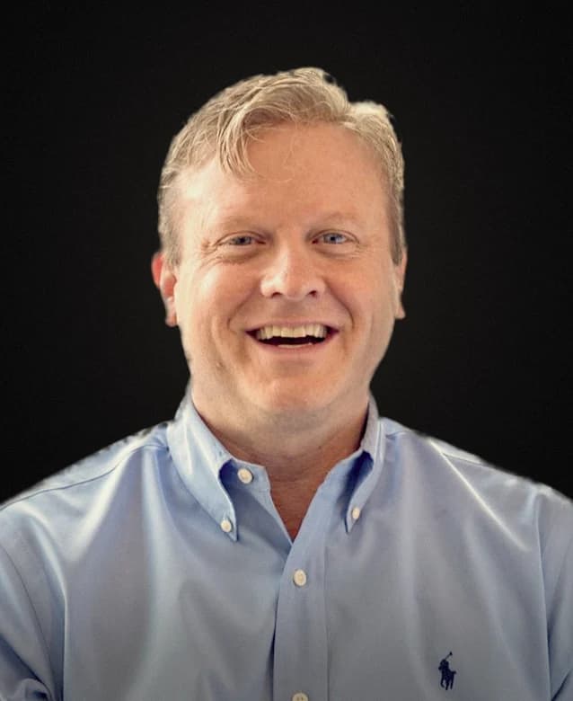 Retrato de Michael McCarthy, sorrindo, de camisa azul