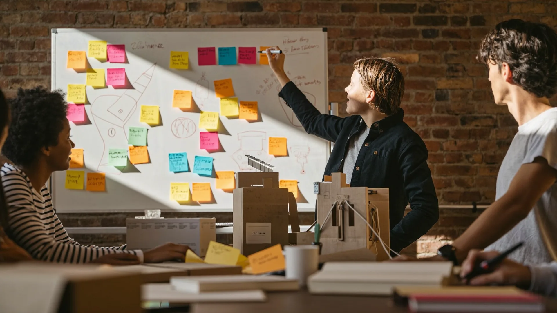 Young team working at a whiteboard covered in notes in a startup space